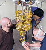 Researchers surround an open dilution refrigerator that cools the SET unit to near absolute zero. Clockwise from left: Michael Stewart, Bahman Sarabi, Neil Zimmerman.